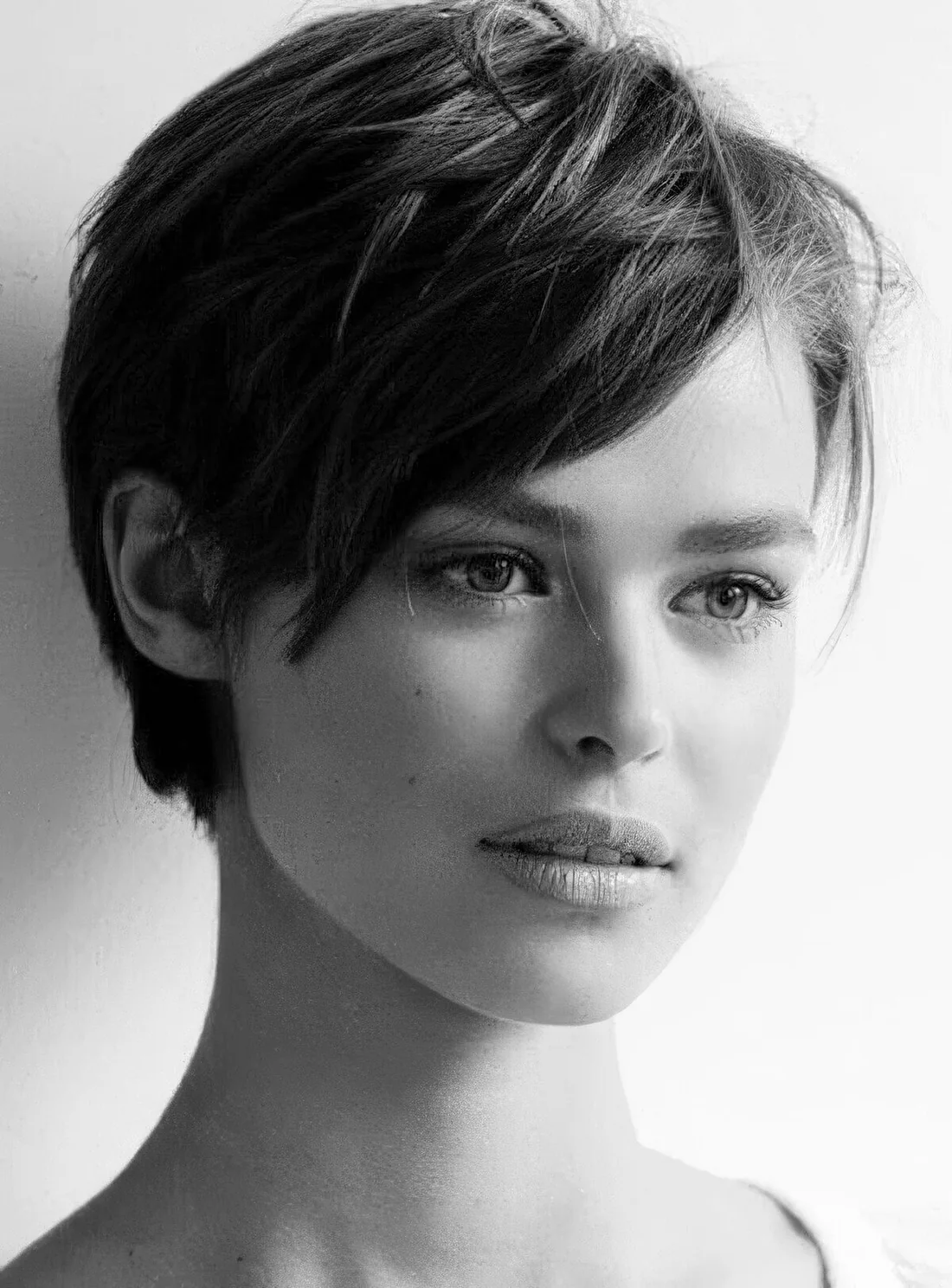 Textured layered pixie on thick hair, with longer side bangs.