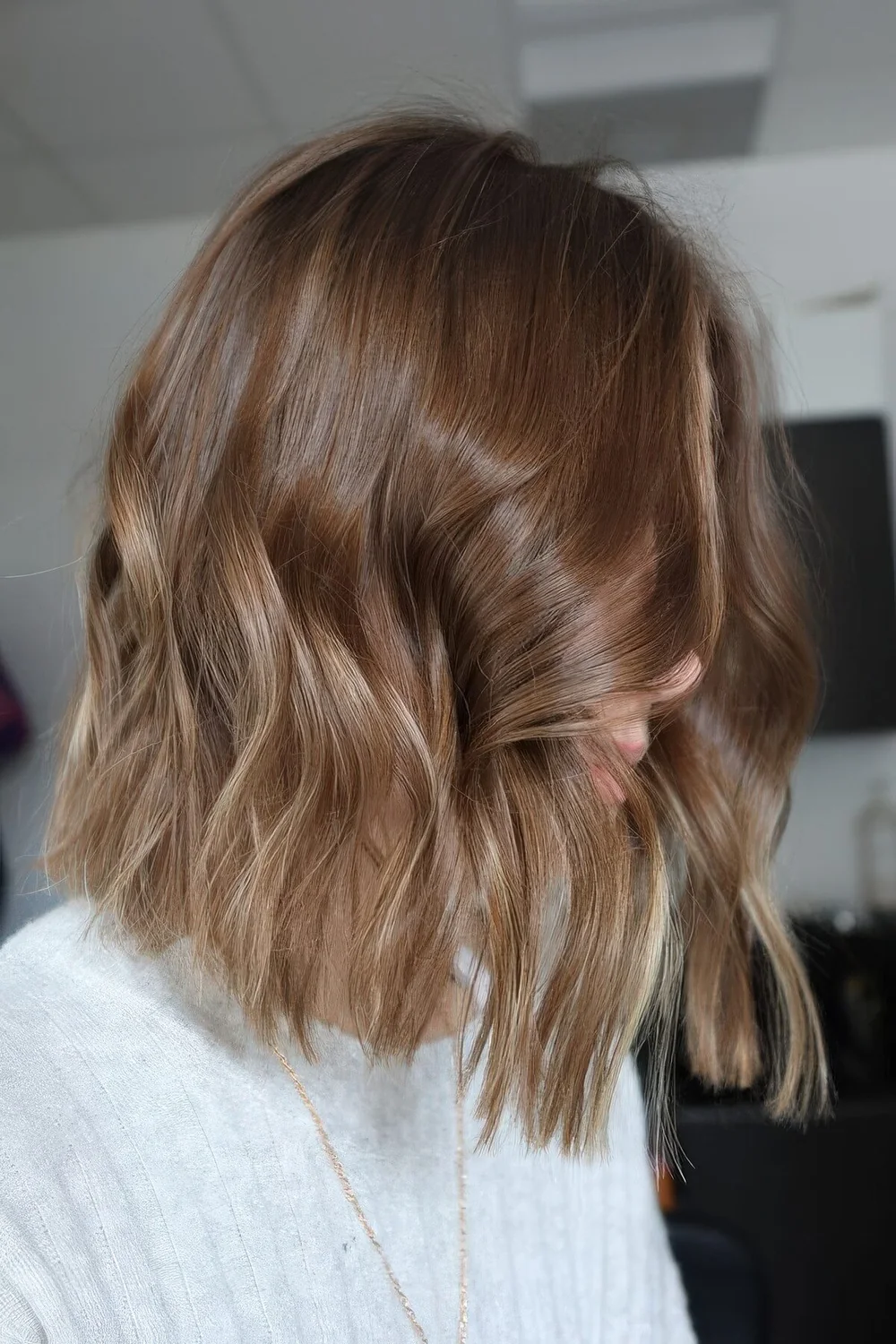 Shoulder-length light brown bob with blonde highlights and some waves.