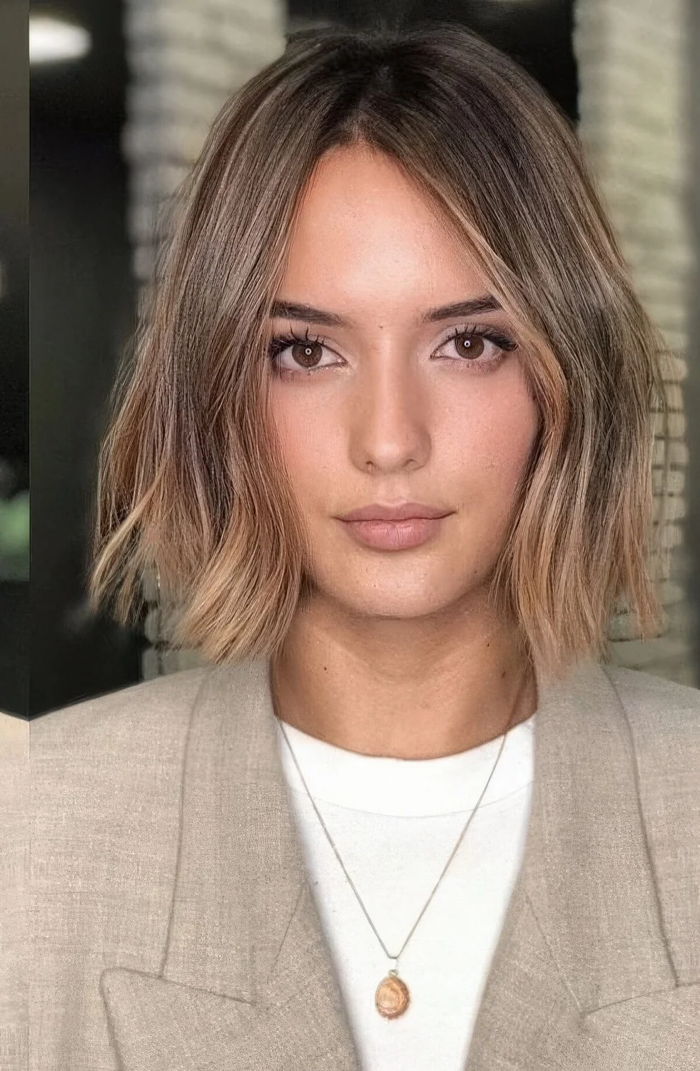 Brown bob with darker root and caramel and gold balayage, with irregular parting and slight waves.