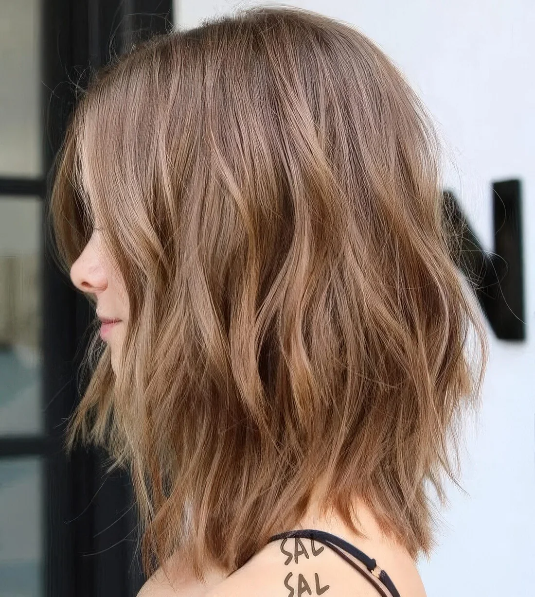 Brunette wavy and layered long bob with lighter bronde highlights.