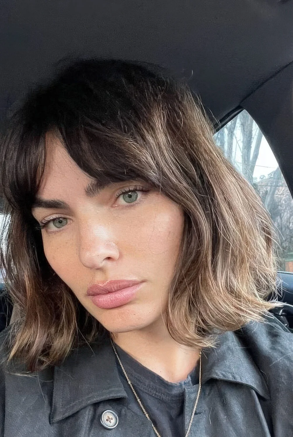 Brunette long bob with bottleneck bangs and wavy hair.