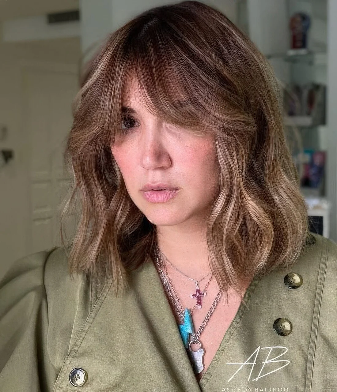 Light brunette long bob with blonde highlights and curtain bangs plus waves.