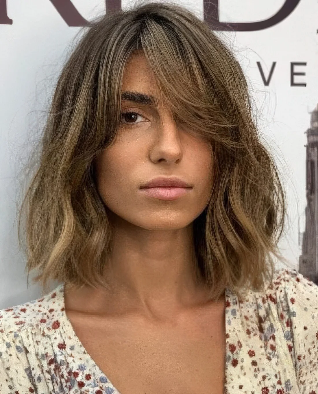 Messy bronde long bob with a darker root and waves plus curtain bangs to soft the look even more.