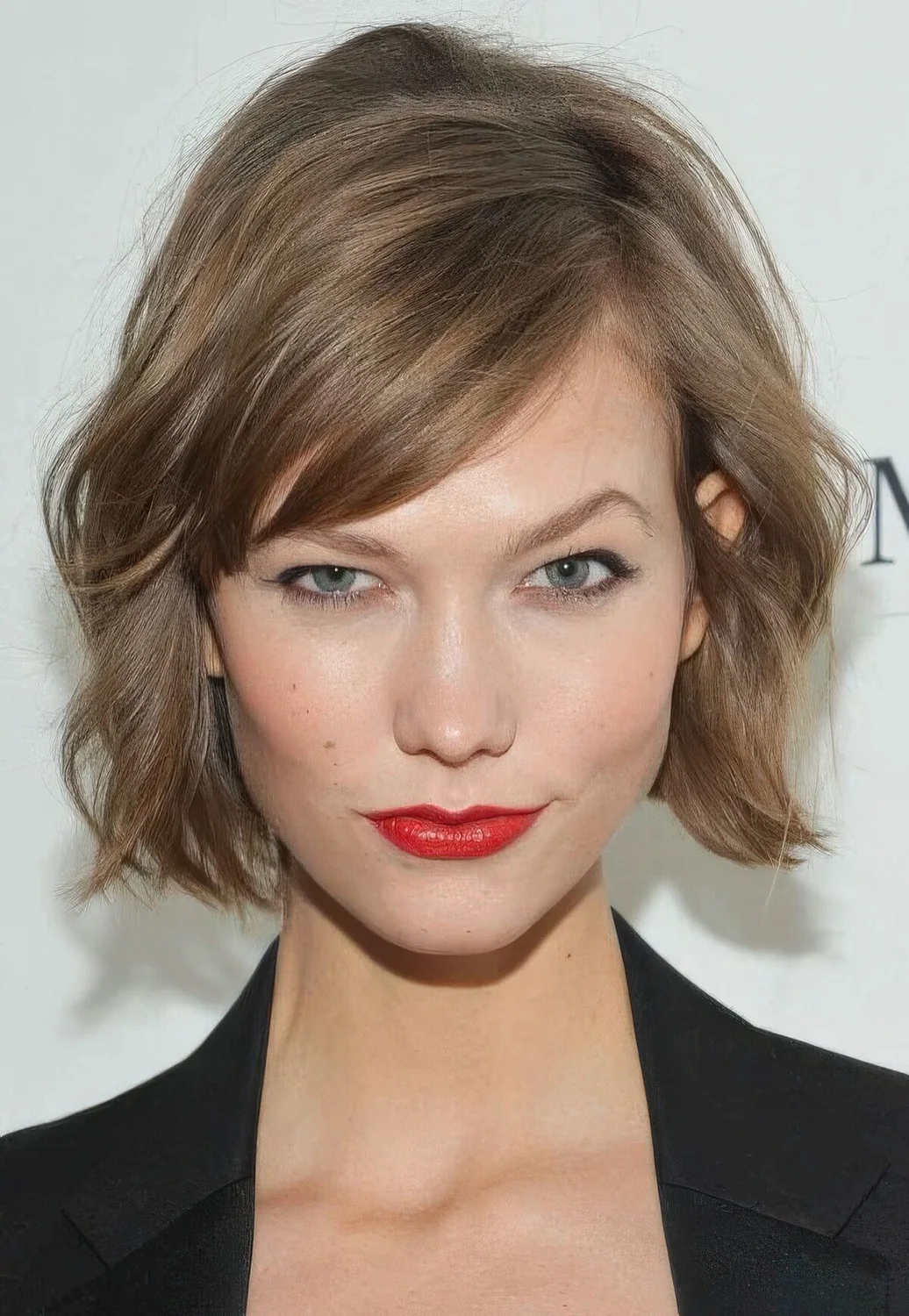 Mousy brown jaw-length bob with side bangs and messy waves.