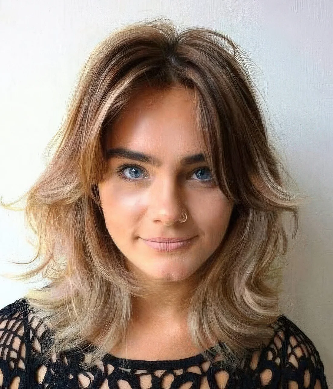 Light burnette shaggy bob with blonde balayage, center part, side bangs and waves.