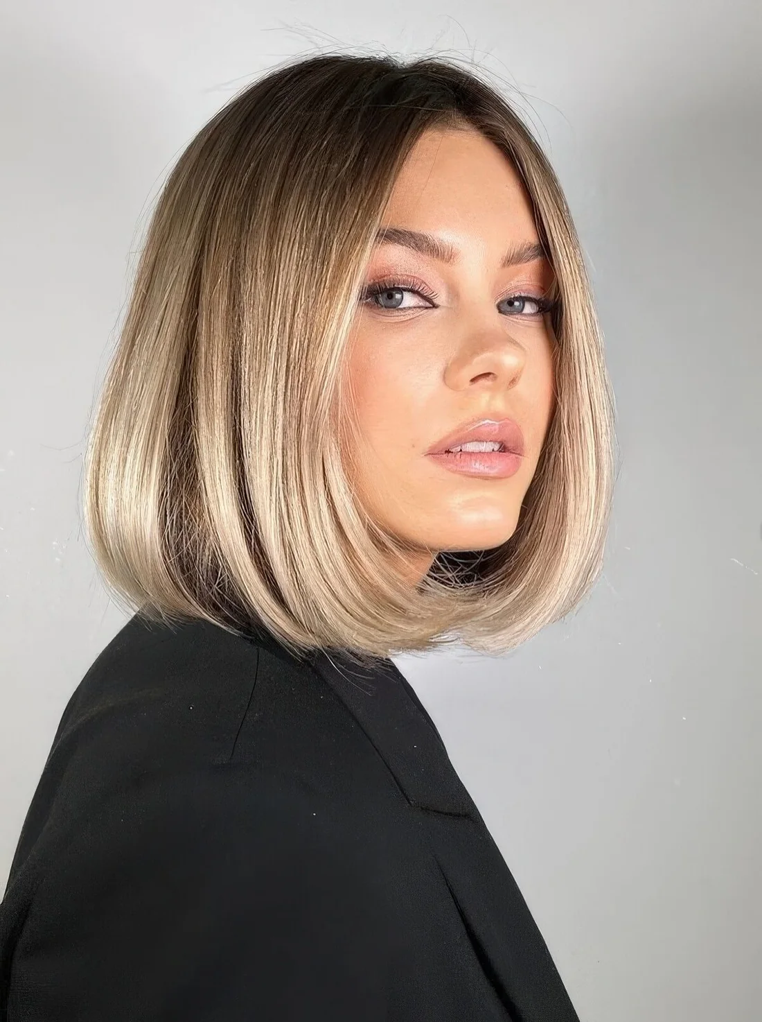 Blonde liquid bob with a darker root and wavy ends.