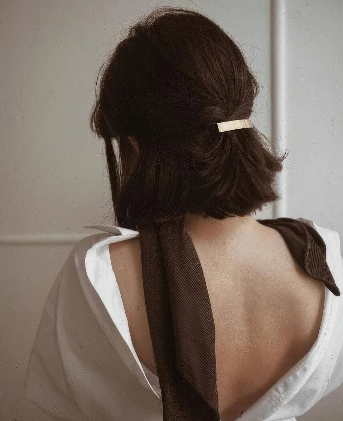 Classic half updo with a volumetric bump on top and a gold hair barrette.