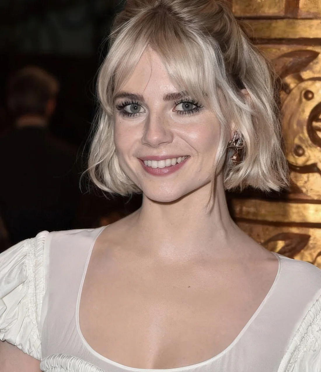 Half updo with face-framing bangs, waves and a bump on top.