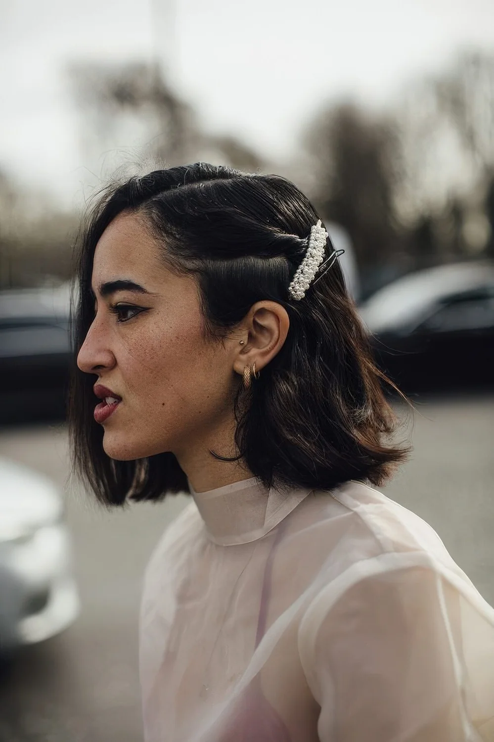 Wavy long bob with side part, a chic pearl hair piece.