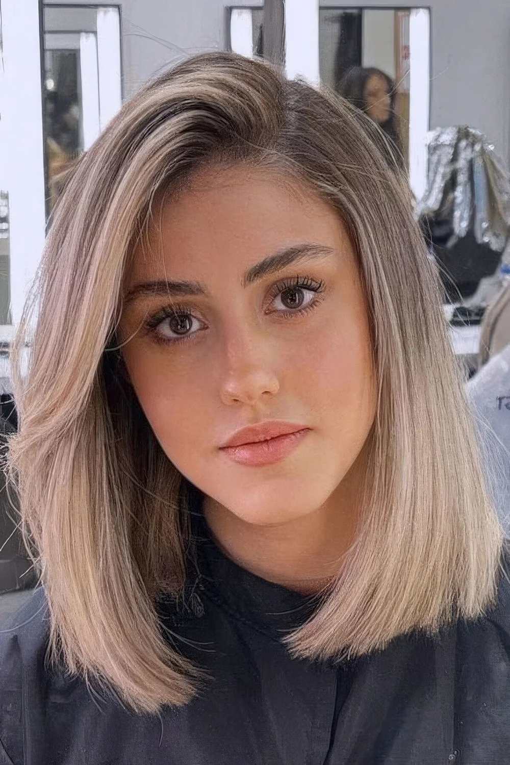 Blonde long bob with a darker root and curved ends.