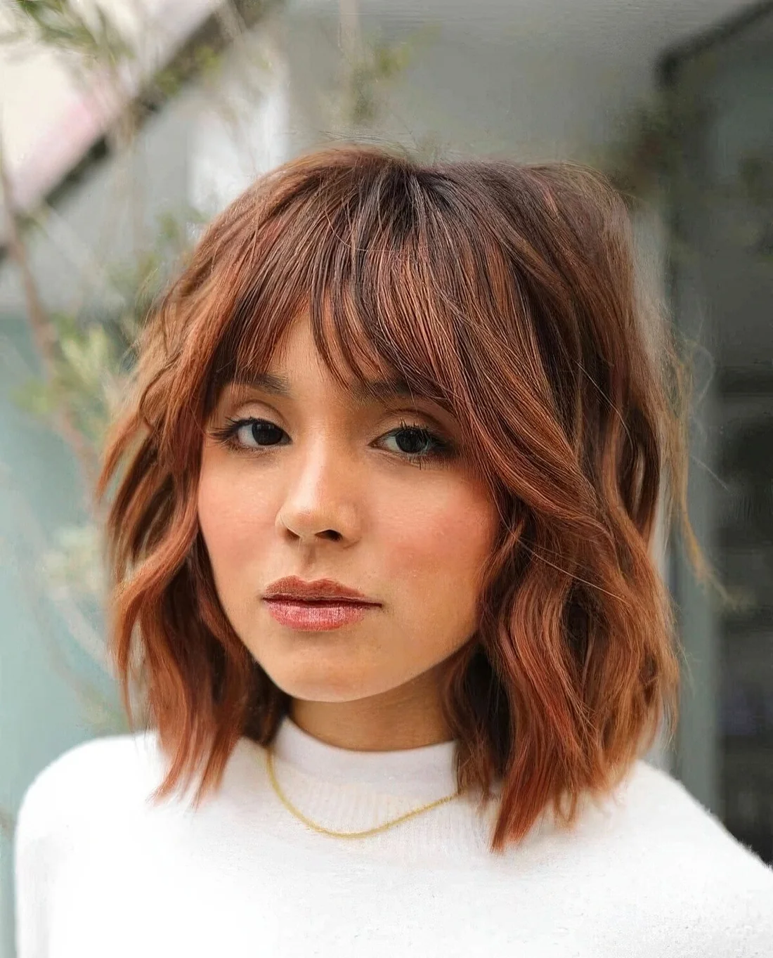 Copper shaggy long bob with a darker brown root and choppy layers.