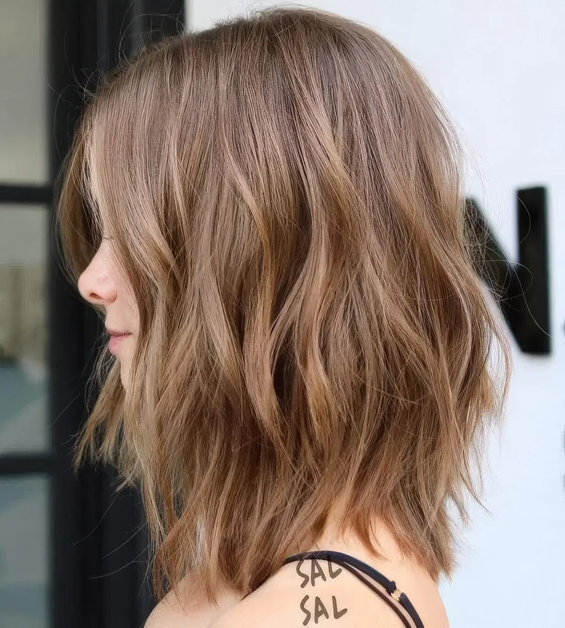 Brunette wavy and layered long bob with lighter bronde highlights.