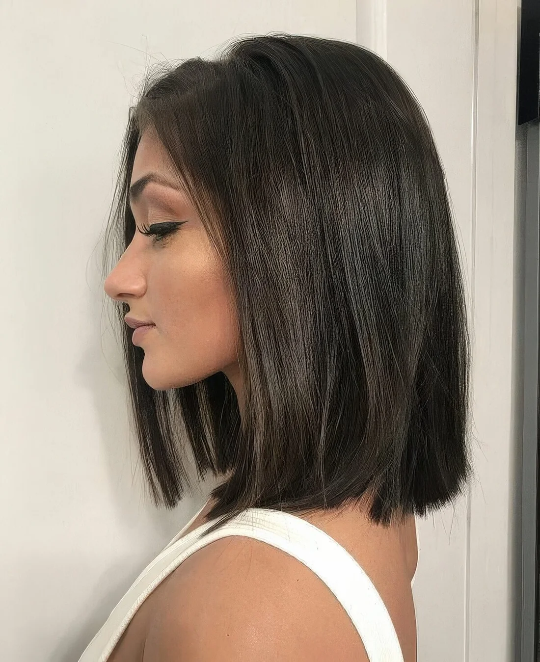 Dark brunette shoulder-length blunt bob.