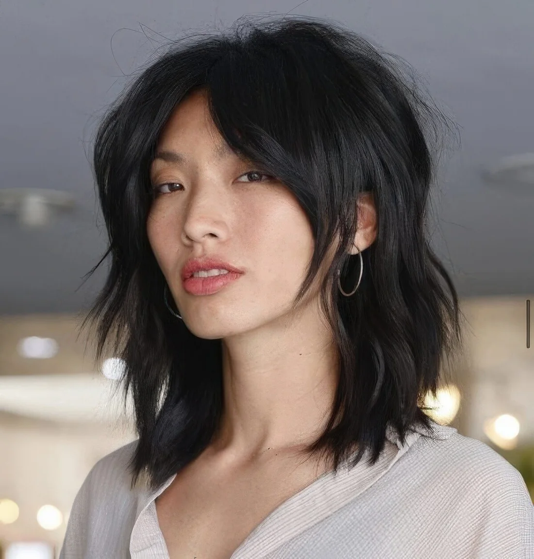 Black shaggy long bob with bottleneck bangs and a messy volume.