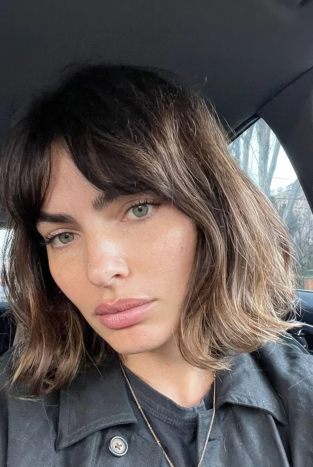 Brunette long bob with bottleneck bangs and wavy hair.