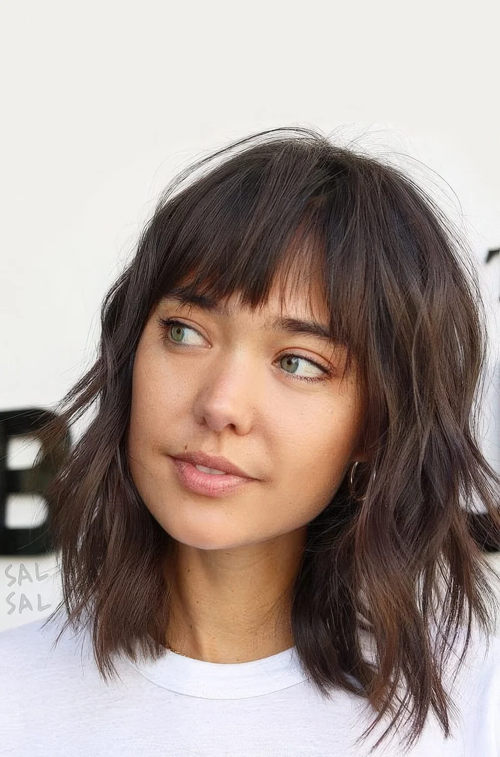 Shaggy dark brunette long bob with bottleneck bangs and waves.