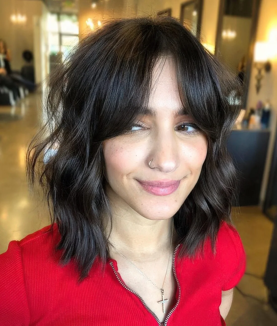 Dark brown shaggy long bob with messy waves and bottleneck bangs.