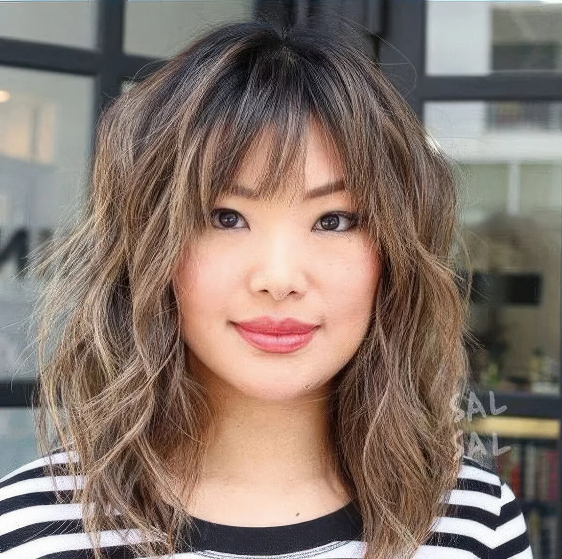 Shaggy long bob with caramel highlights and wispy and bottleneck bangs.