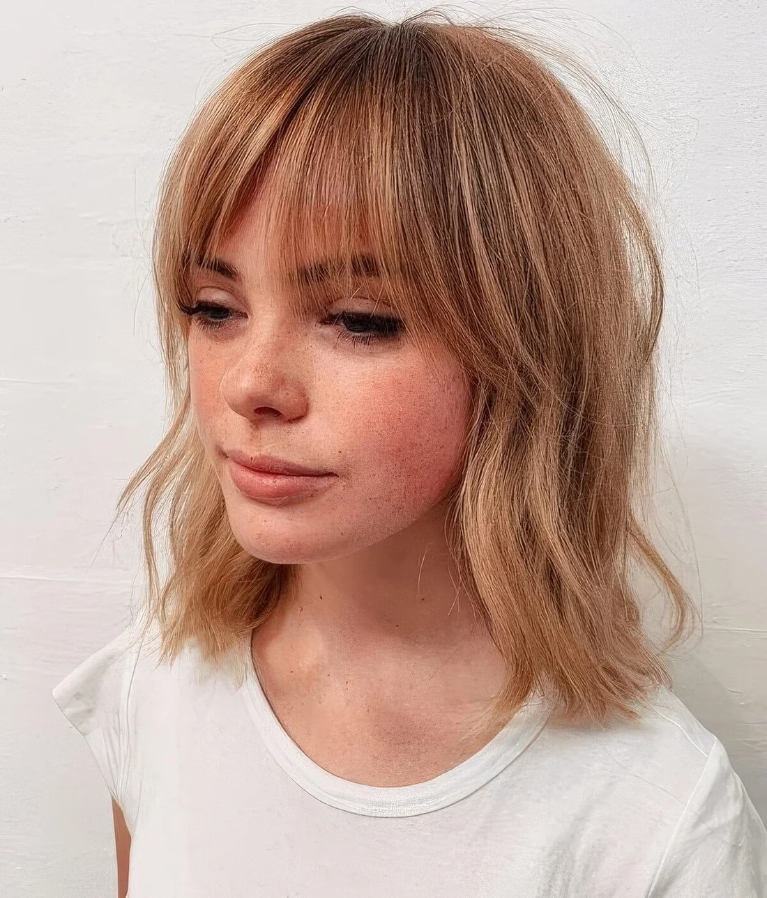 Light copper hair with messy waves and bottleneck bangs.