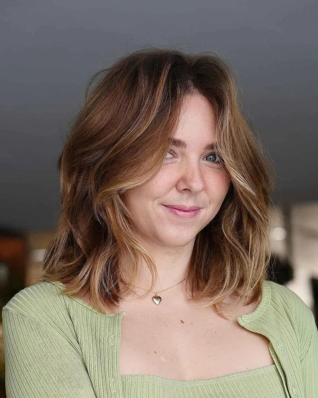 Soft brown lob with lbonde highlights and a lot of volume plus curtain bangs.