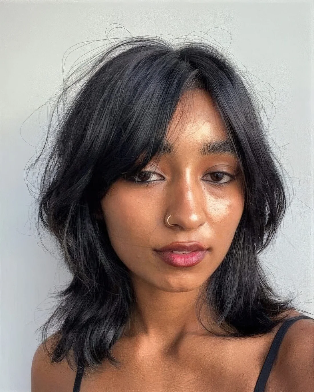 Black outgrown bob with center part and curtain bangs plus waves and texture.