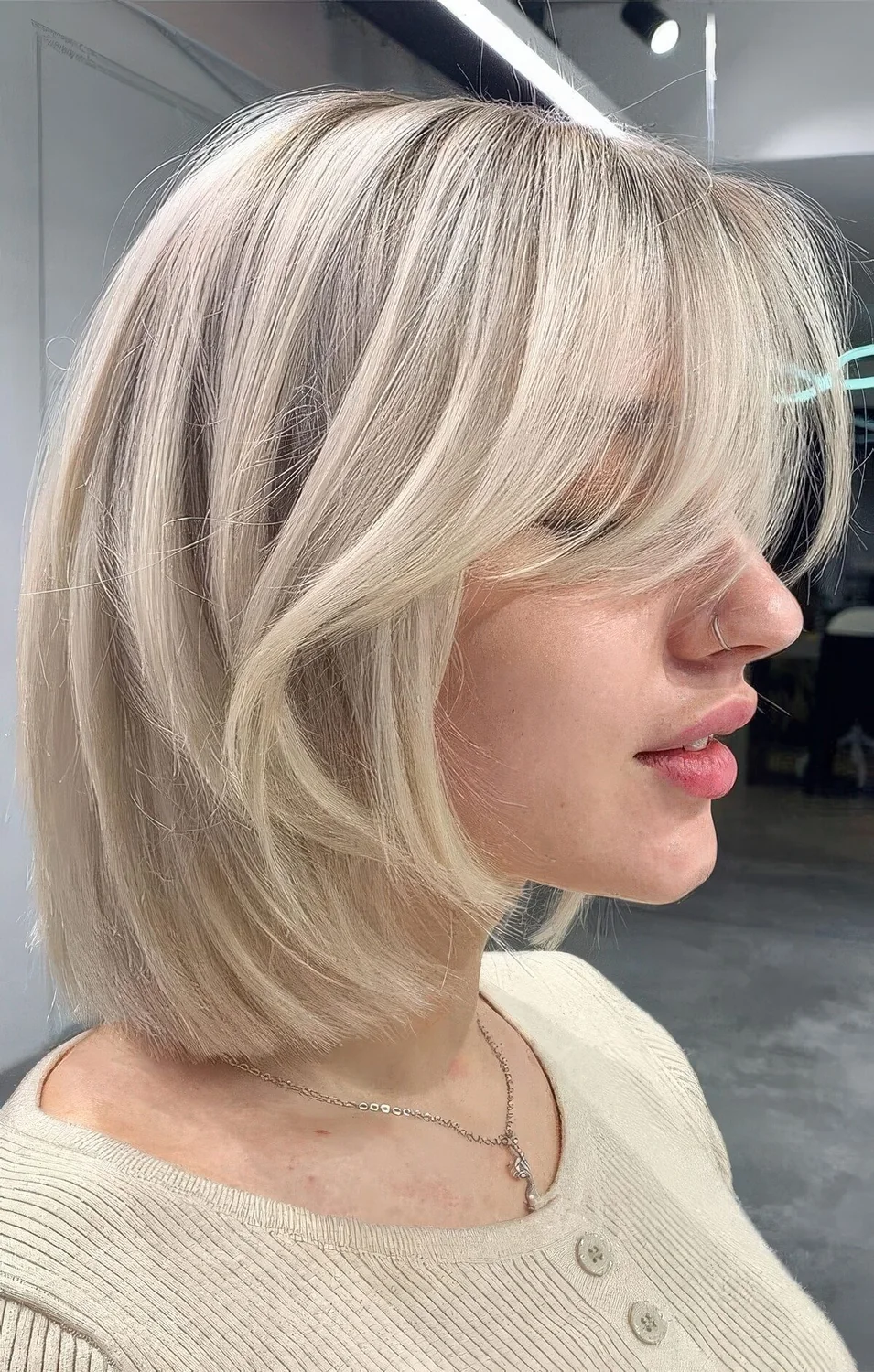 Chic icy blonde long bob with curtain bangs.