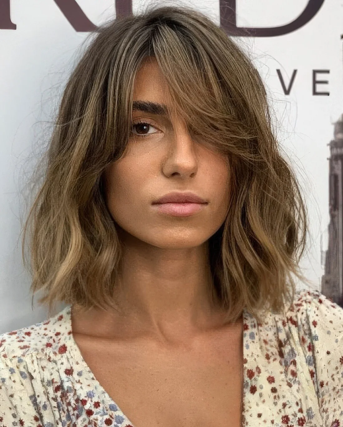 Messy bronde long bob with a darker root and waves plus curtain bangs to soft the look even more.