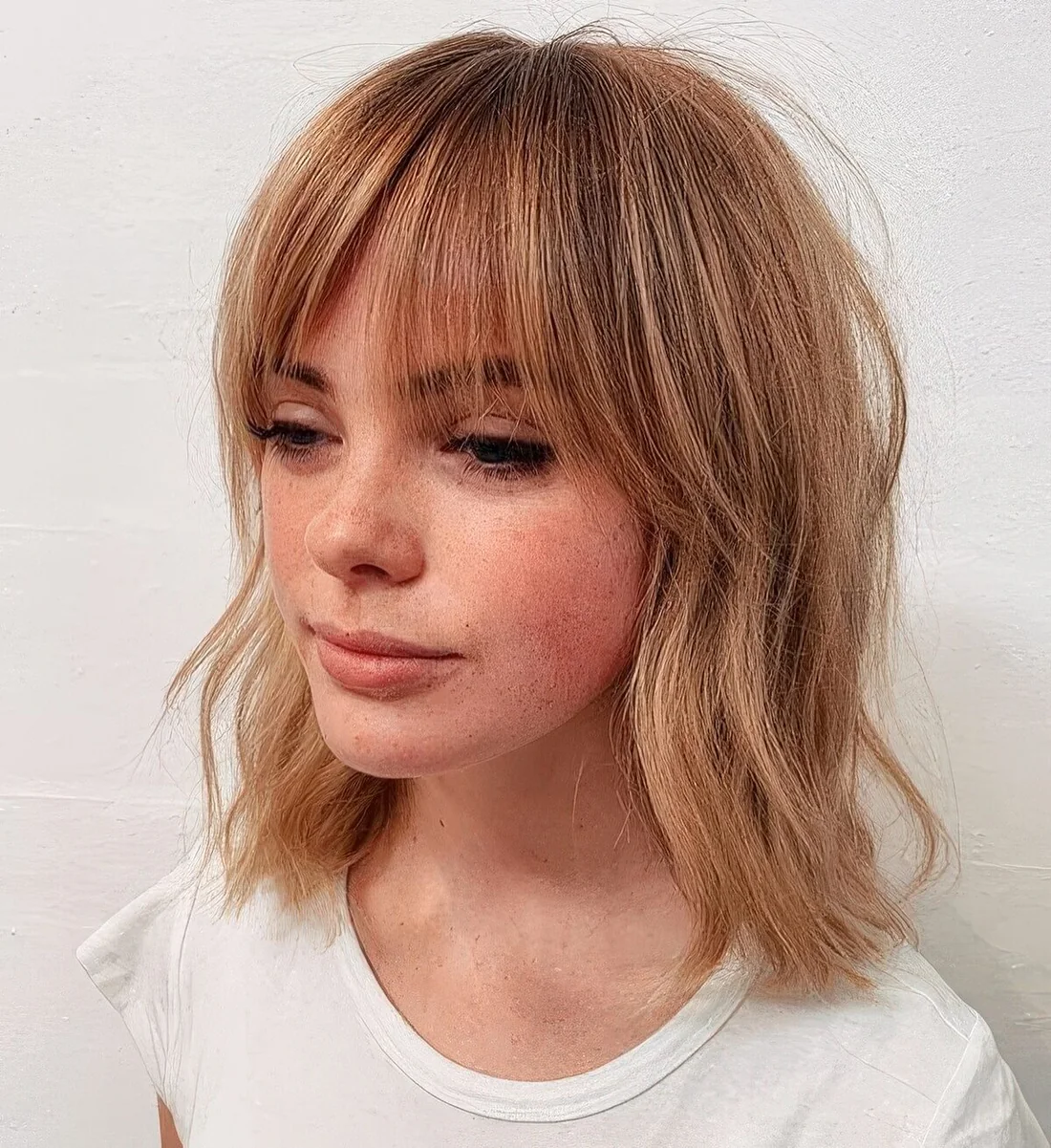Ligth ginger long bob with messy waves and wispy bangs.