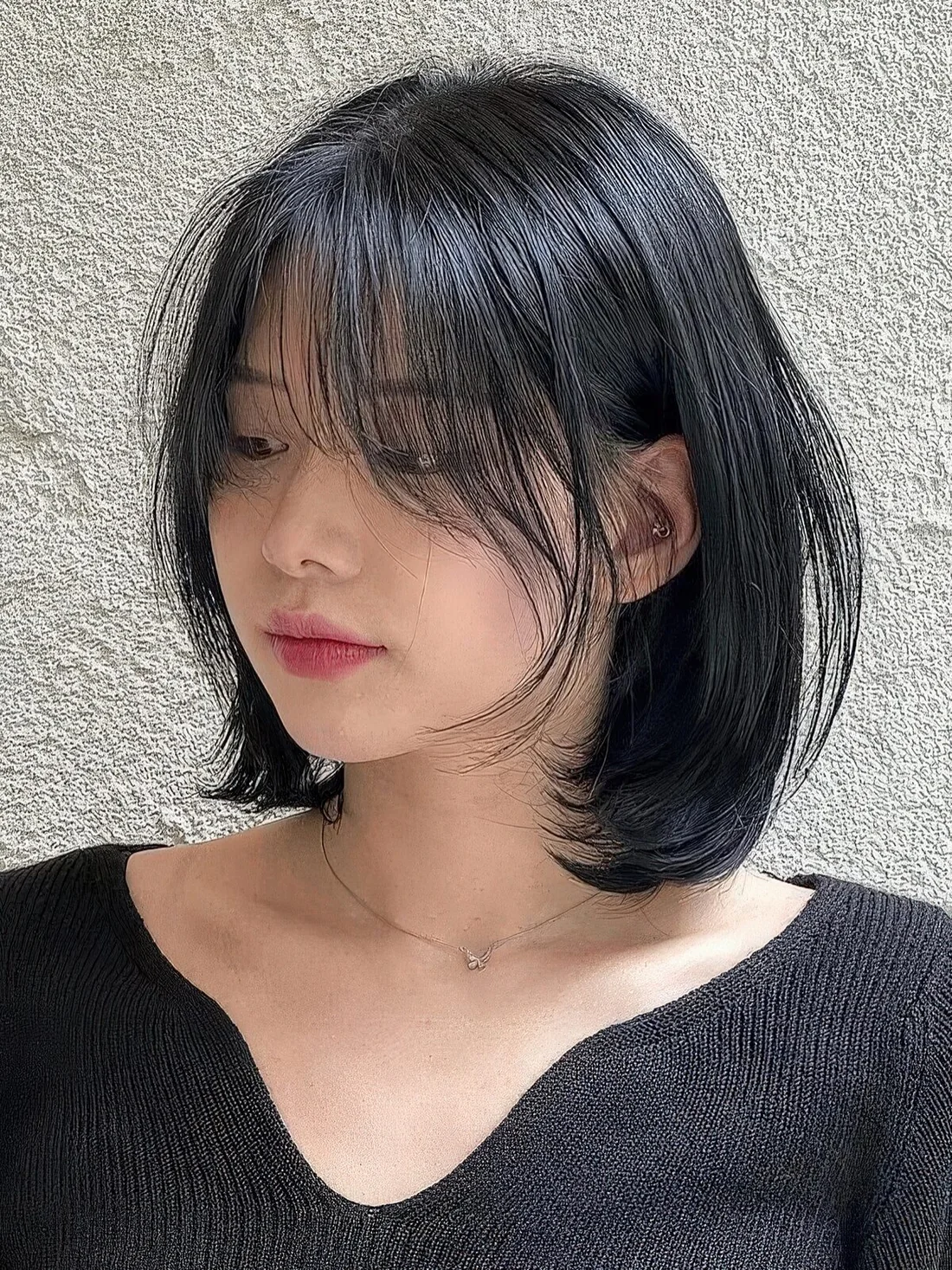 Long black bob with curved ends and long wispy bangs that beautifully frame the face.