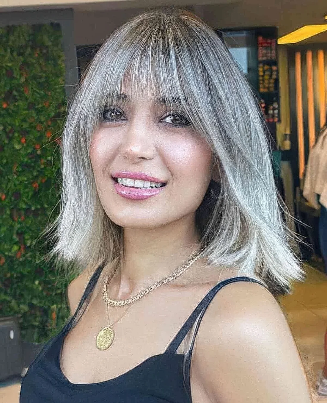 Salt and pepper long bob with wispy bangs.