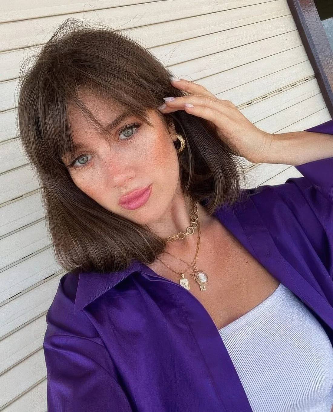 Medium-length brunette hair with wispy bangs.
