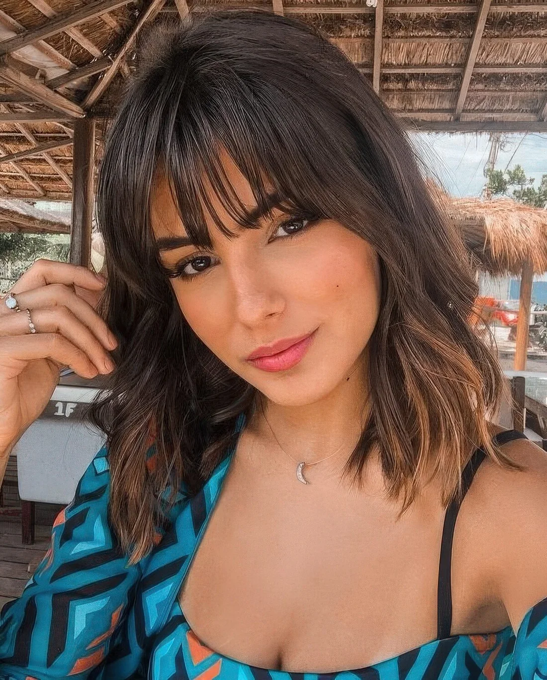 Medium-length dark brown hair with texture and chestnut lowlights plus layered bangs for a pretty look.