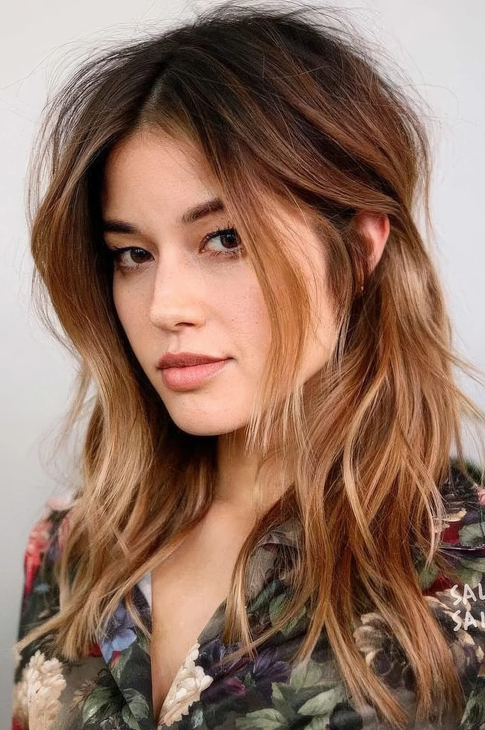 Dark brown root plus ombre caramel ends and messy waves plus layered bangs.