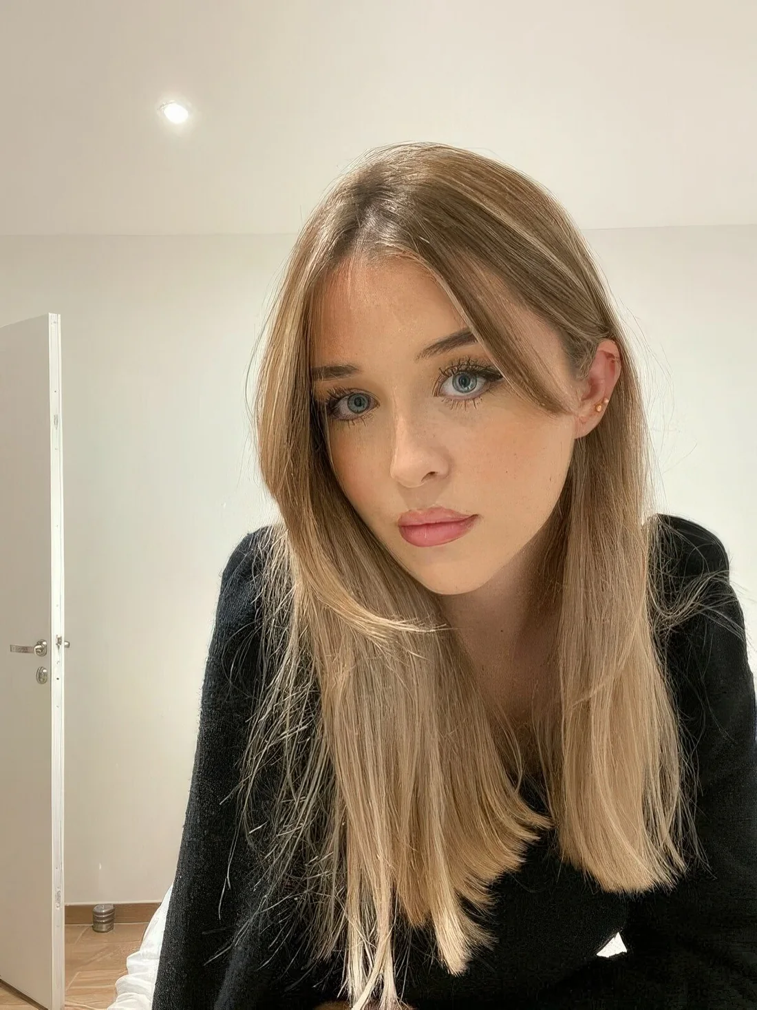 Long blonde hair with balayage and long curtain bangs.