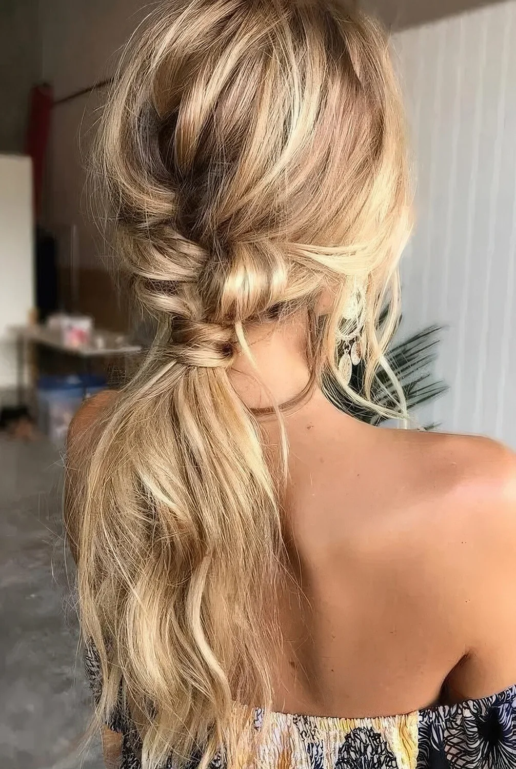 Twisted messy ponytail with a braid and a messy top plus textural hair and face-framing locks.