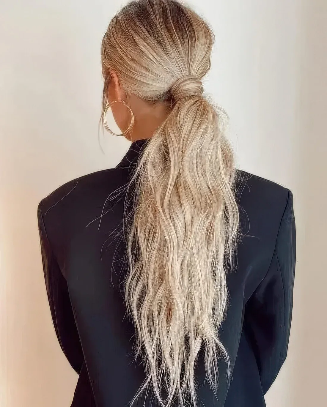 Messy and textural low ponytail with a messy top and hair wrapping it.