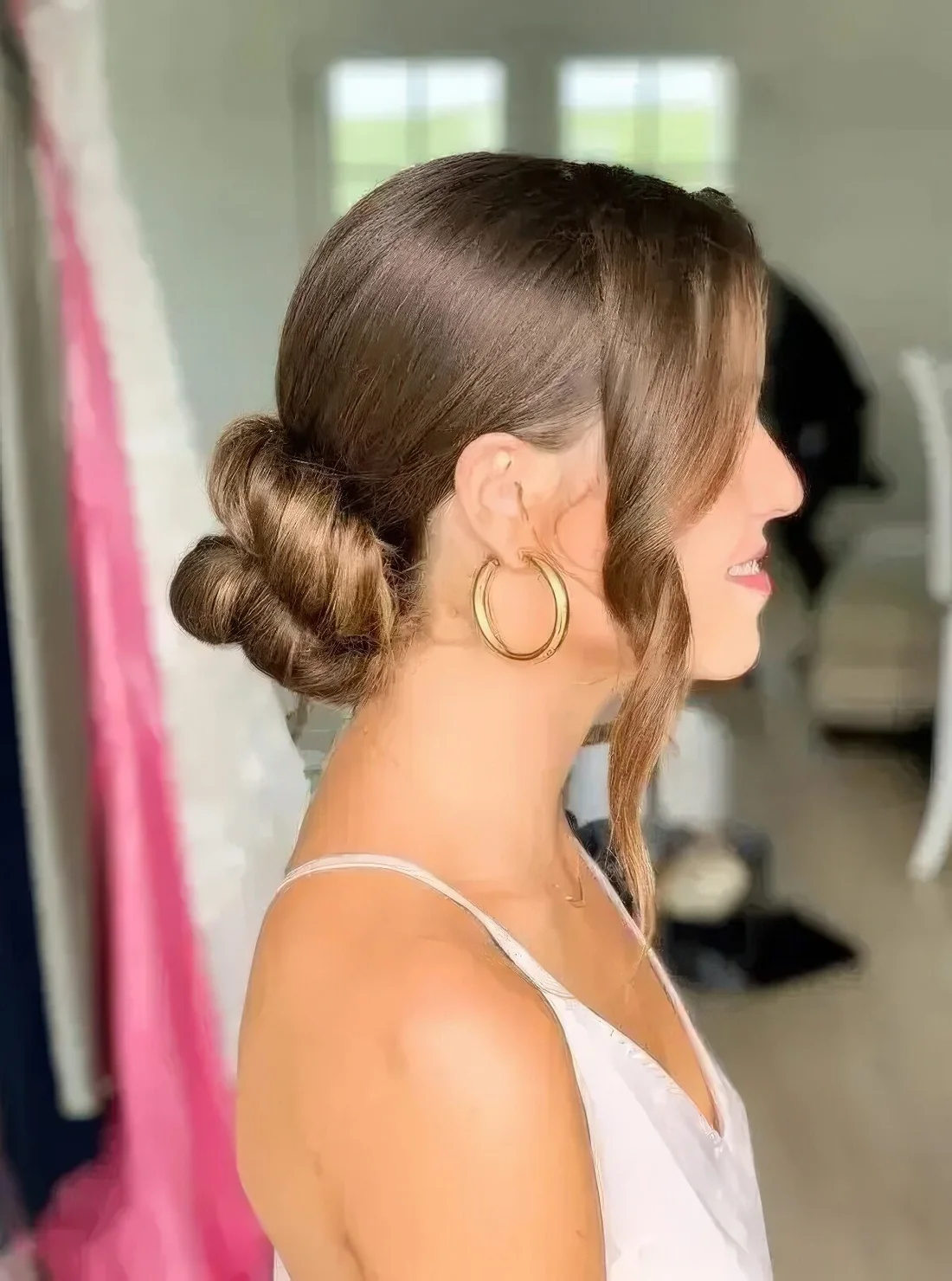 Twisted low bun with a sleek top and some wavy locks framing the face.