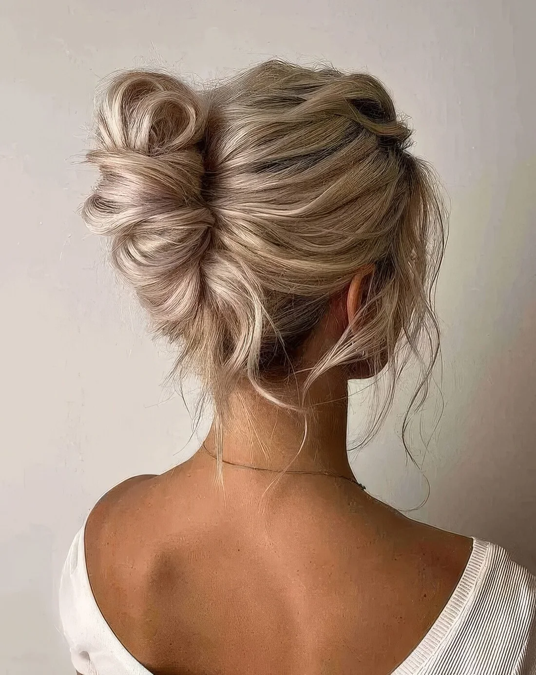 Messy and twisted chignon hairstyle with a messy wavy top and some locks down.