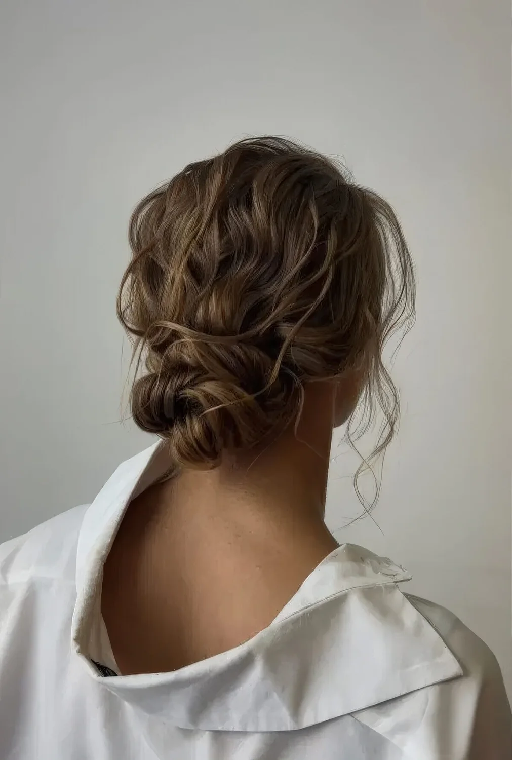 Wavy messy low bun with a wavy top and some locks down.