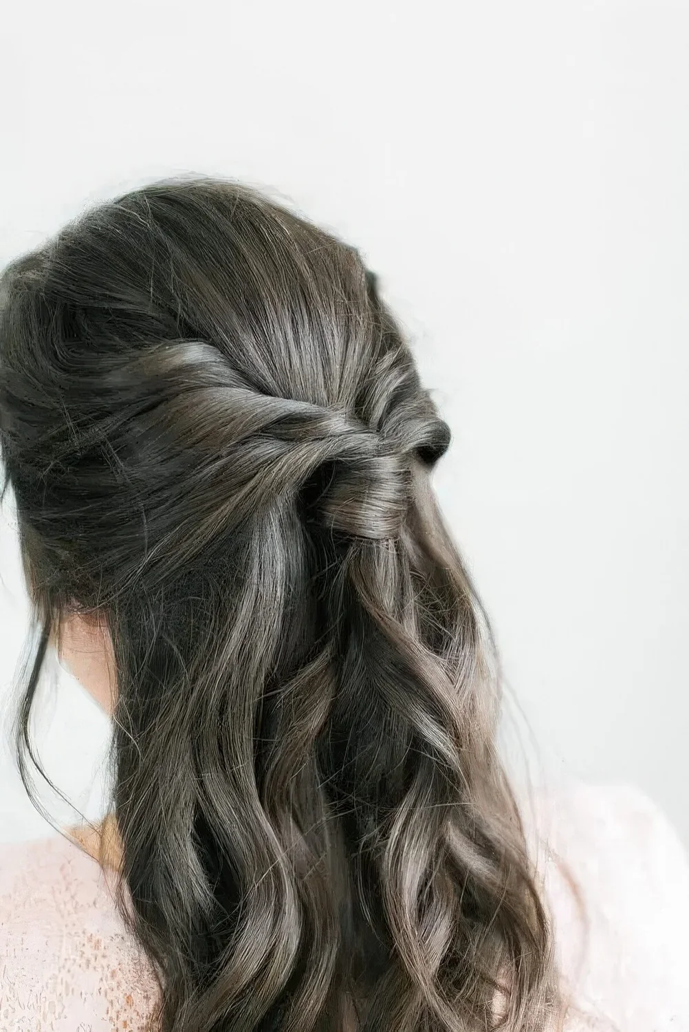 Boho half updo with a sleek top, a twisted ponytail and waves down.