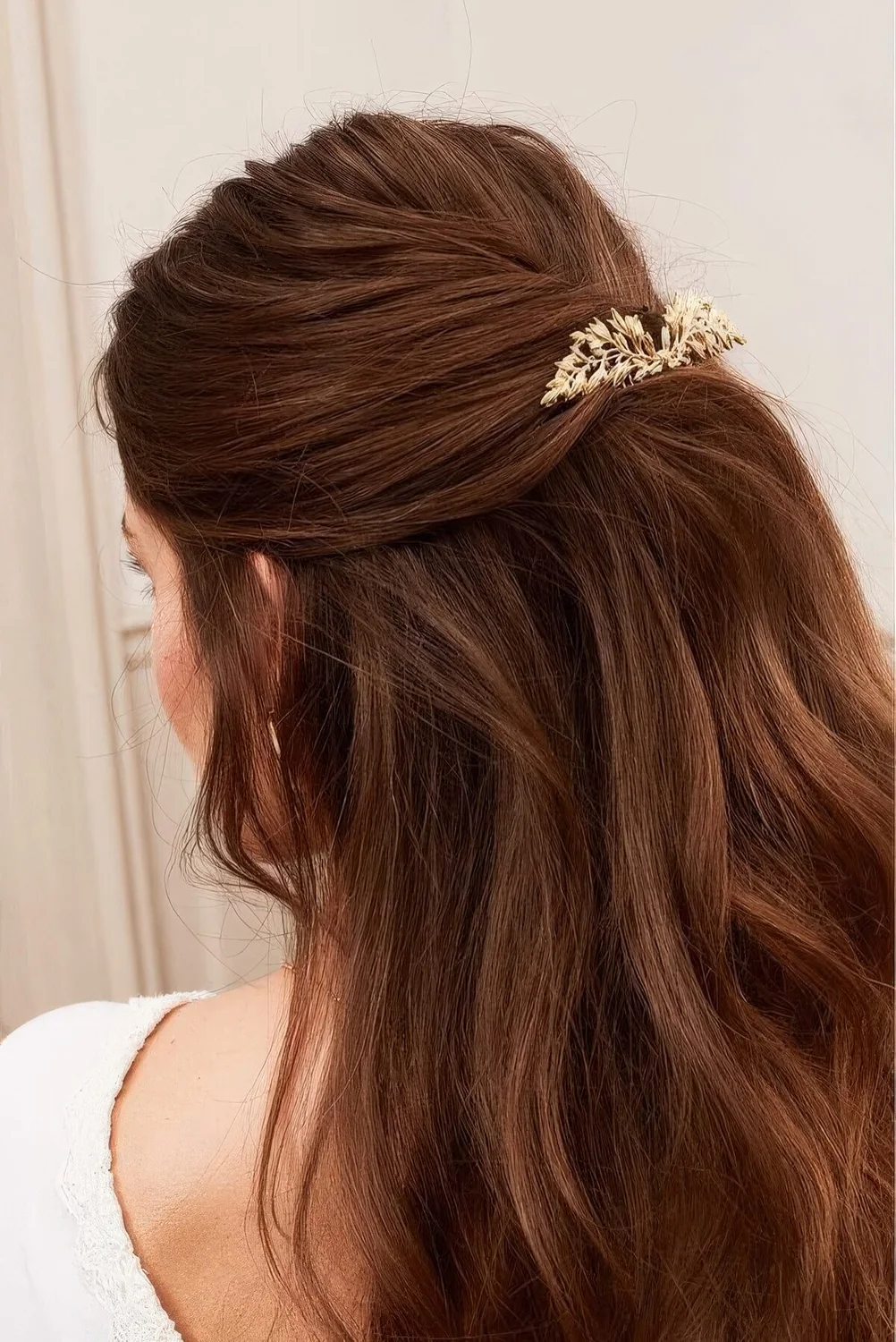 Half updo with a twisted low ponytail and some volumetric wavy hair with a catchy hairpin.