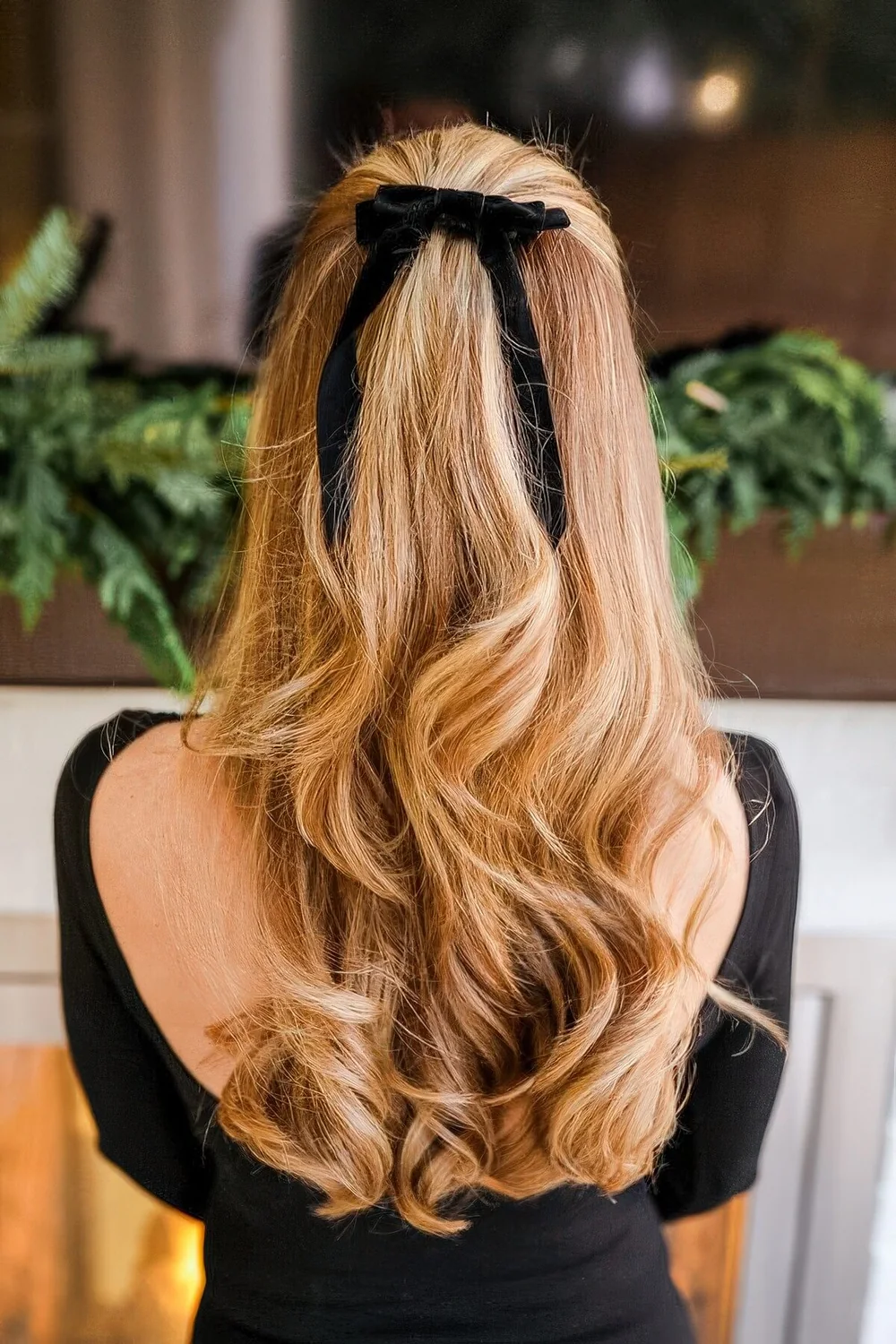 Half updo with waves and volume plus a black velvet bow.