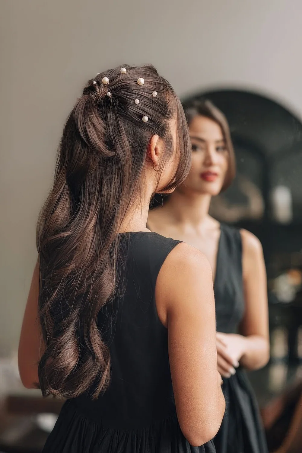 Long half updo with a ponytail, pearls on top and wavy hair down.