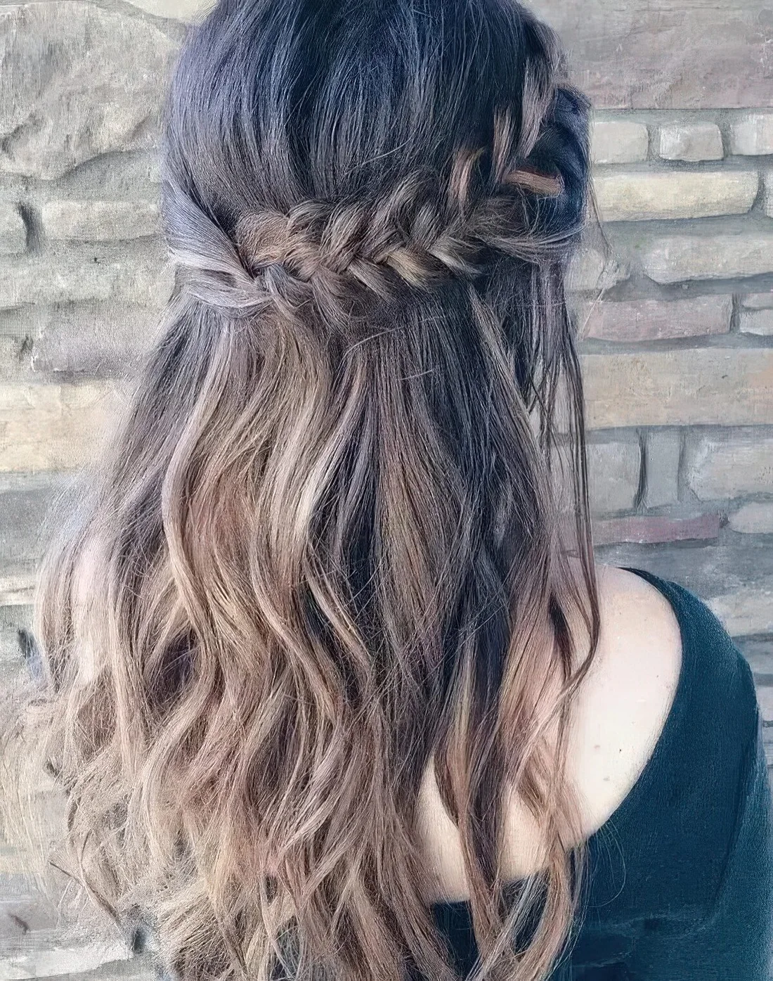 Wavy half updo with a thick fishtail braid on one side and twisted hair on the second.