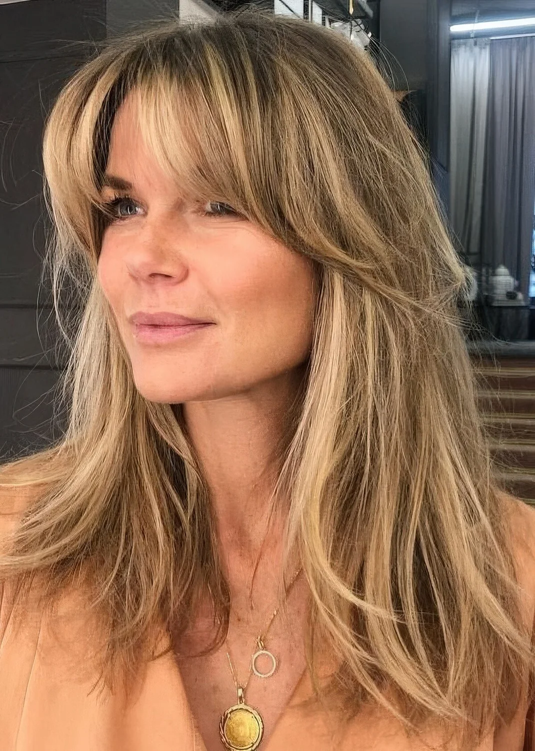 Long blonde hair with highlights and bottleneck bangs.