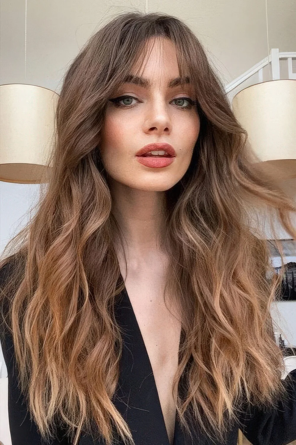 Long brunette hair with a slight ombre effect, bottleneck bangs and waves.