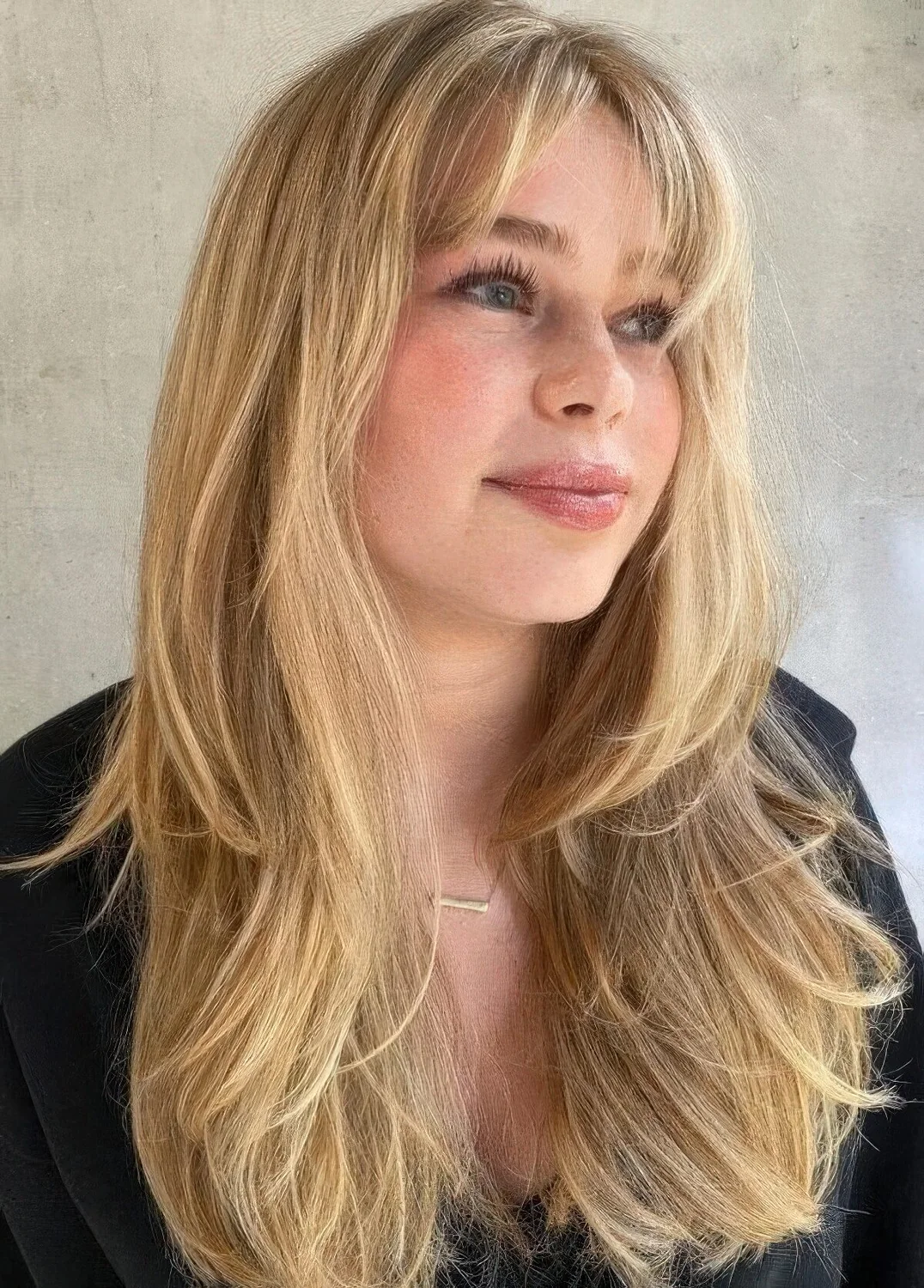Dimensional blonde long hair with a butterfly haircut, with layered flattering bangs and feathered layers.