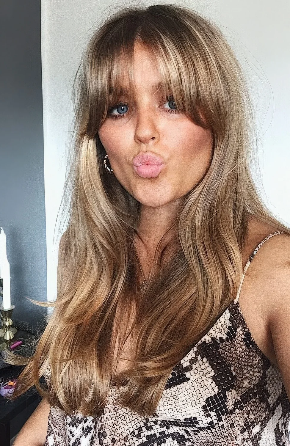 Long blonde hair with highlights and waves and with curtain and bottleneck bangs.