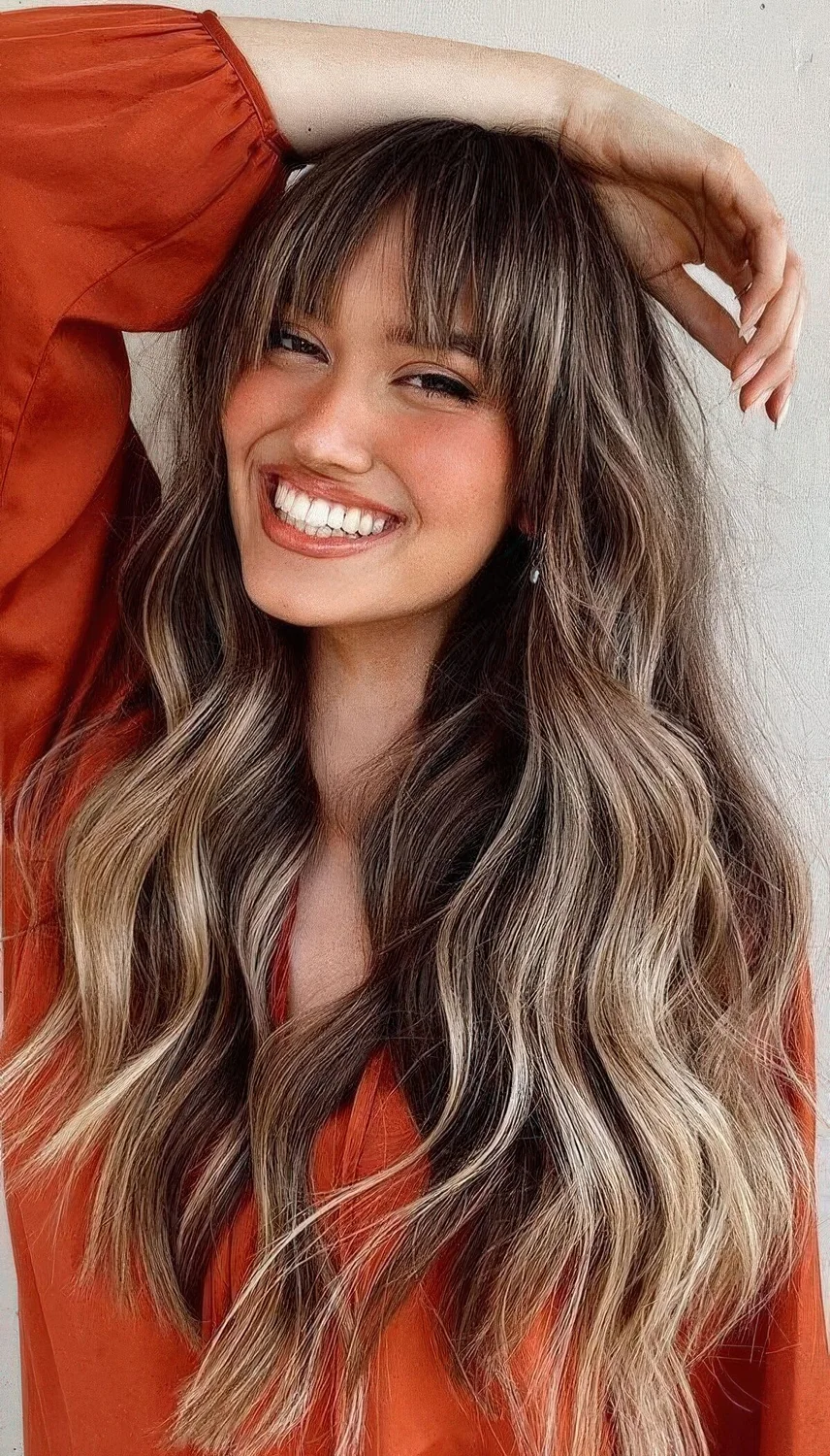 Long brunette hair with blonde balayage and bottleneck bangs.