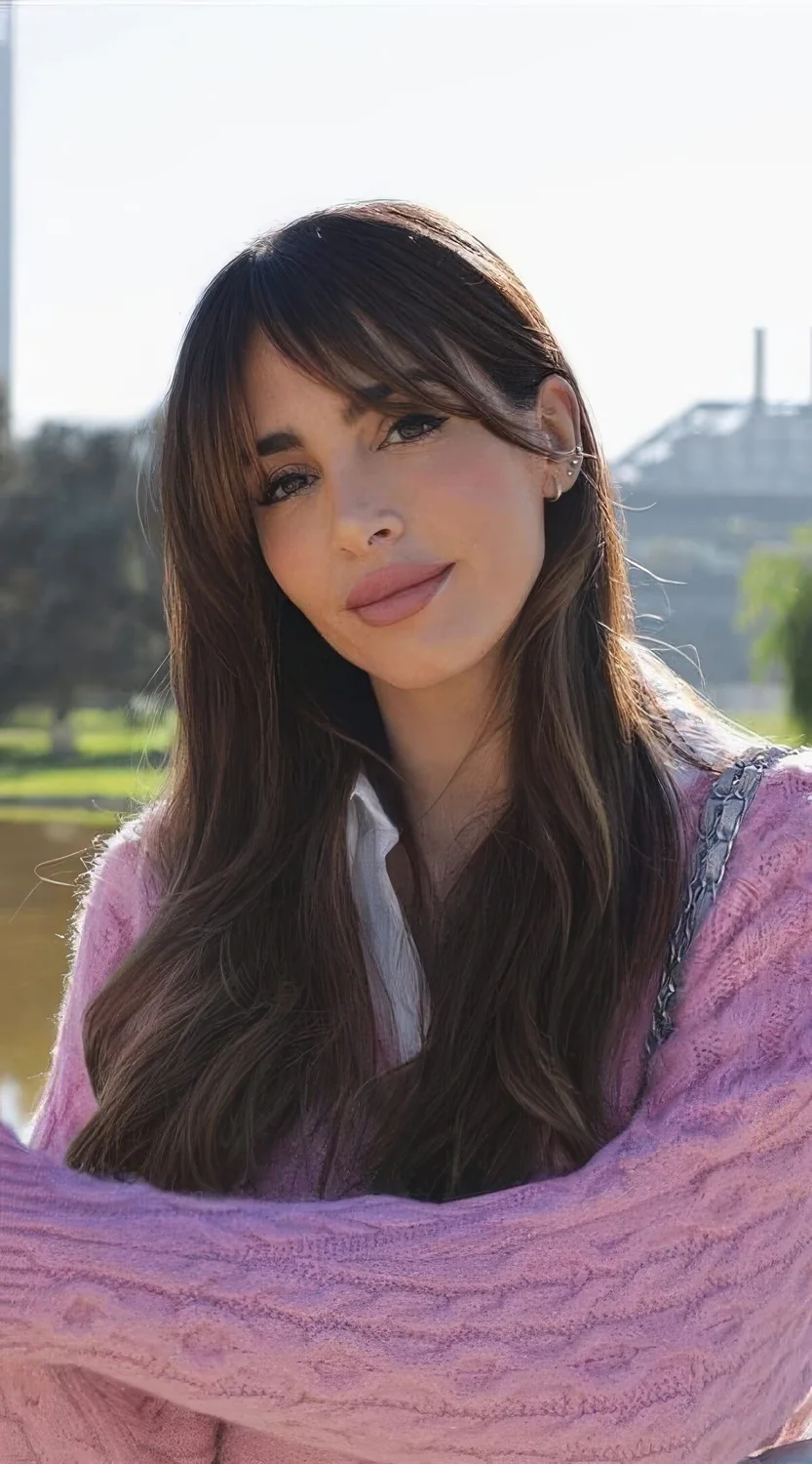 Long dark brunette hair with caramel highlights and bottneck bangs.